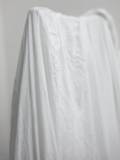 A soft, draped fabric in neutral tones hanging gracefully on a minimalist backdrop.