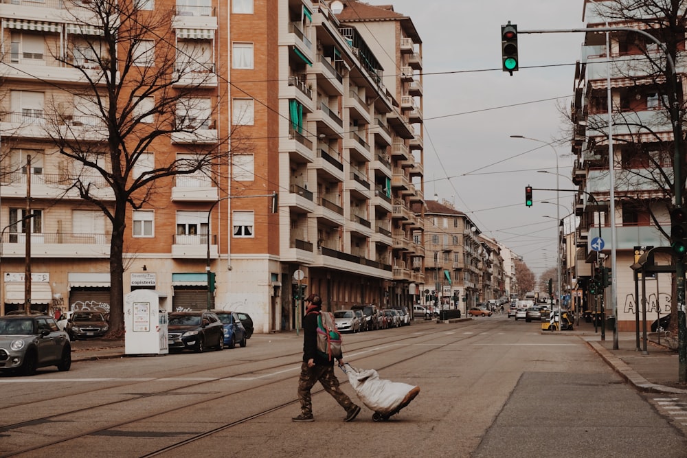 man in black jacket and blue denim jeans walking on sidewalk during daytime