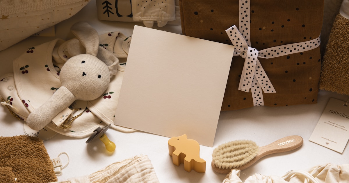 Baby gifts and newborn essentials beautifully arranged with a wrapped present, soft toys, and baby accessories in warm cream and mustard tones.