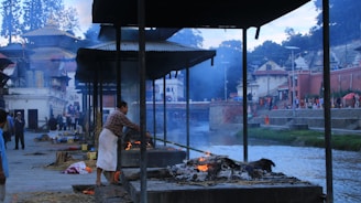 A serene priest performing traditional Hindu last rites by the riverbank at dawn.
