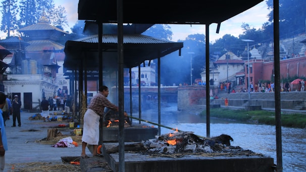 A serene priest performing traditional Hindu last rites by the riverbank at dawn.