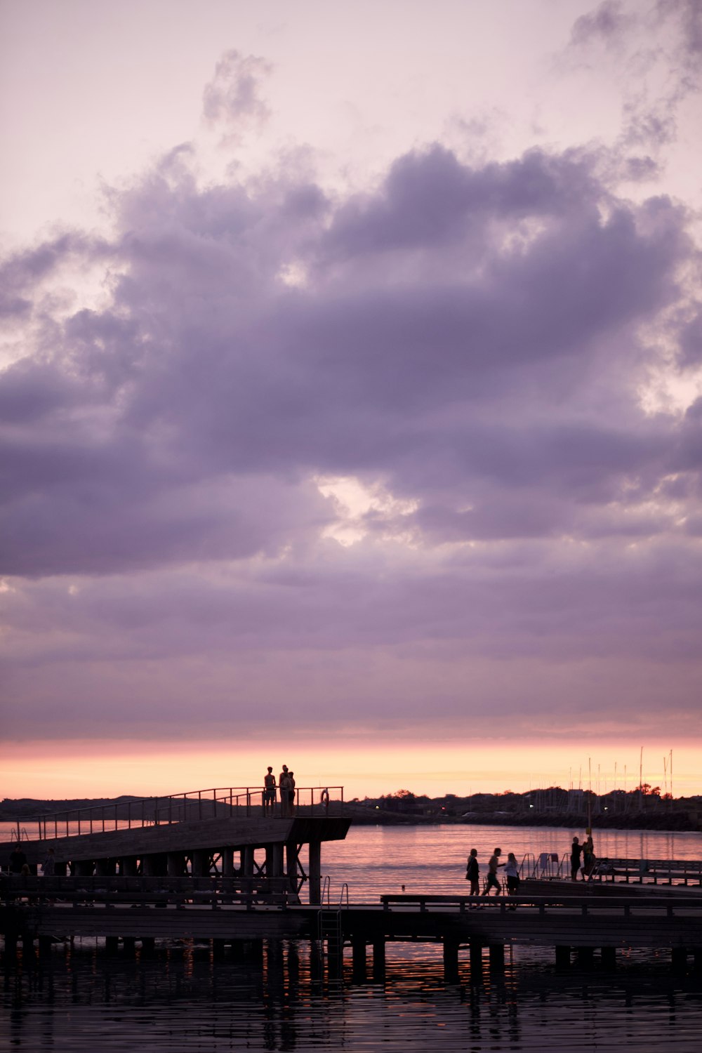 silhouette of people standing on dock during sunset