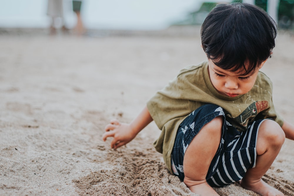 boy in brown shirt lying on brown sand during daytime