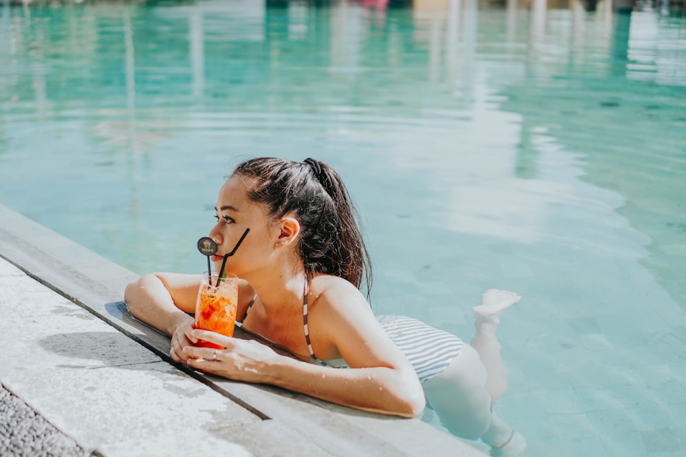 woman in white bikini drinking from orange juice