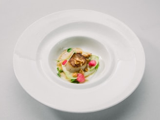 piatto di ceramica bianco con un delizioso piatto di pesce decorato con erbette verdi e petali rossi
