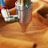 A metal nozzle attached to a blue and red tube presses against a piece of orange fabric.