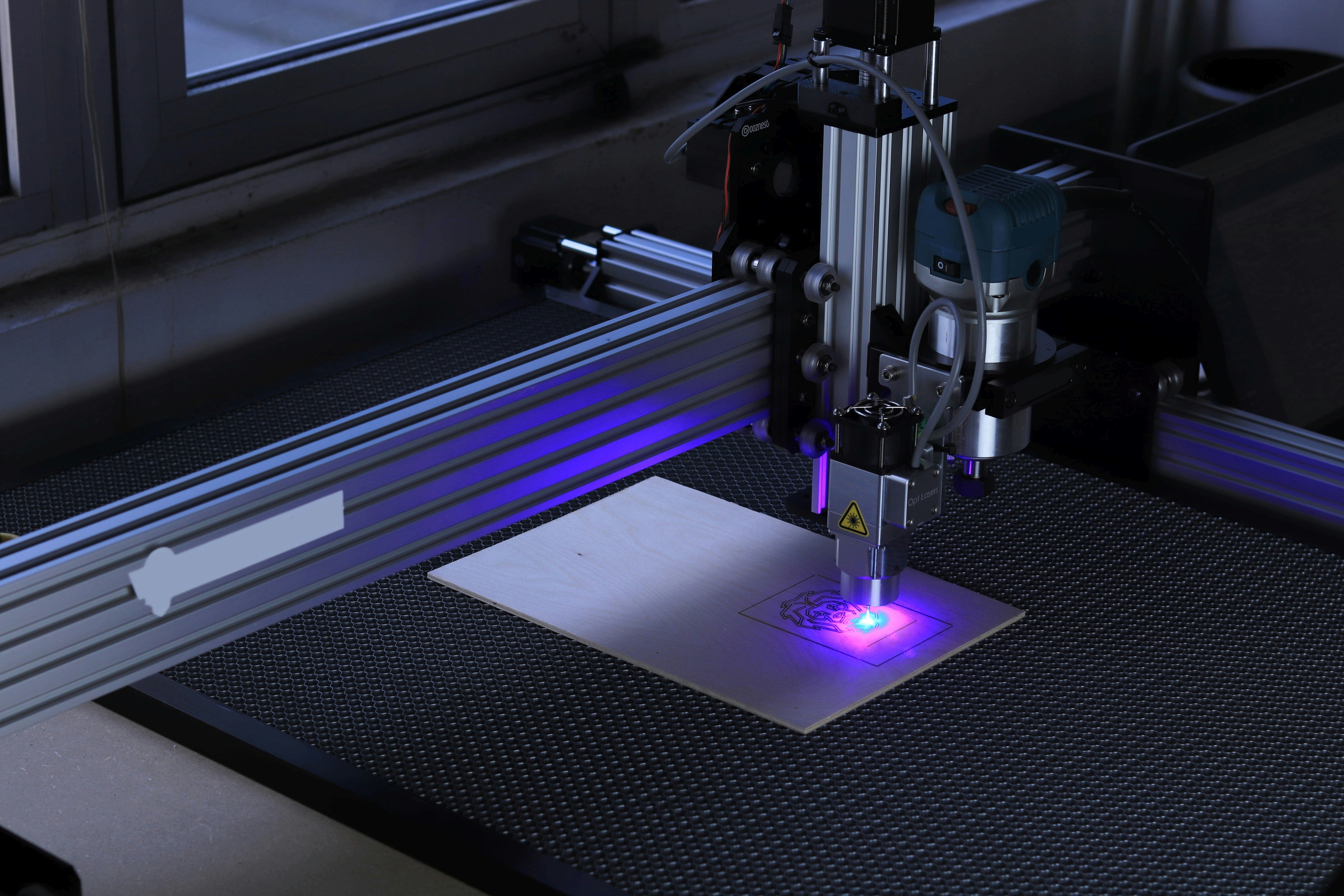 Laser engraving machine creating detailed intricate design on dark wood surface with precision
