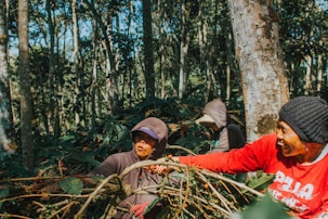 man in brown jacket and brown hat sitting on green grass during daytime