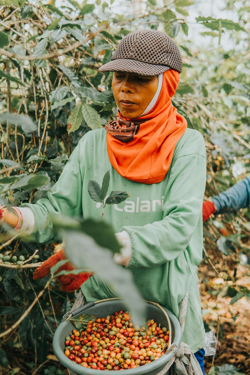 woman in green jacket and orange scarf standing on dried leaves during daytime