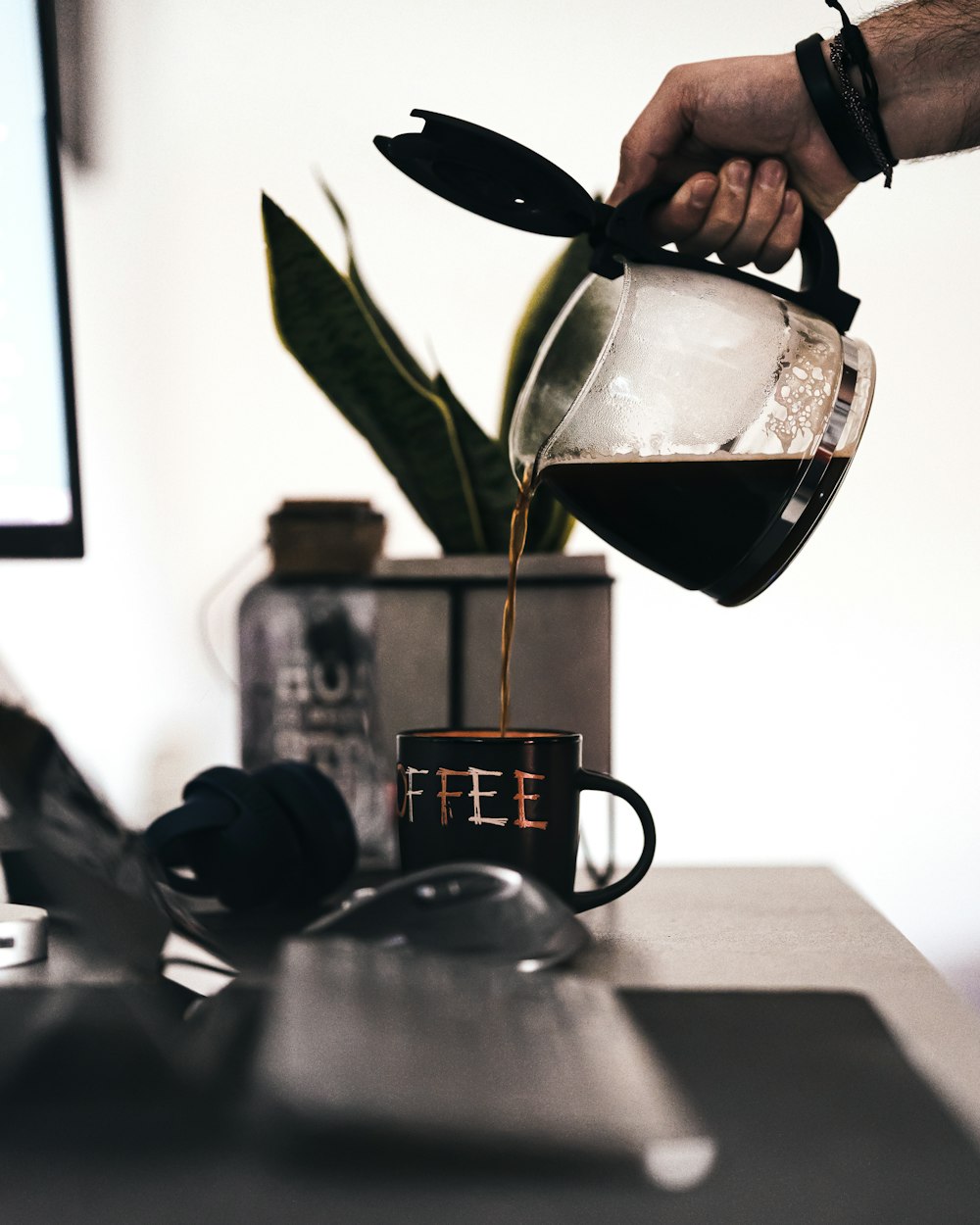 person pouring black liquid on clear glass cup