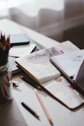 Author's desk with open laptop and scattered notes.