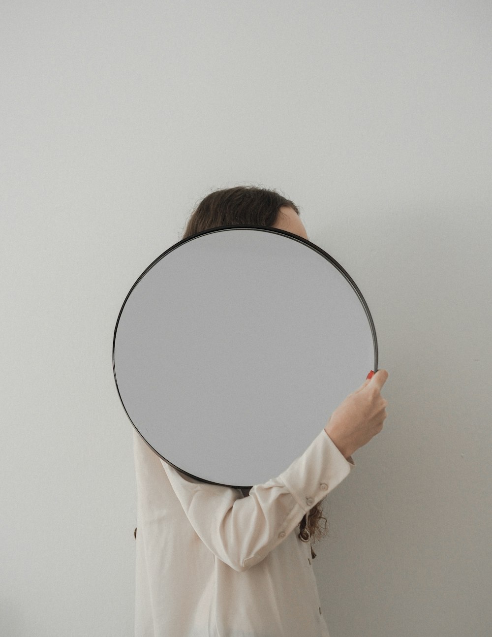 person holding round mirror with white frame