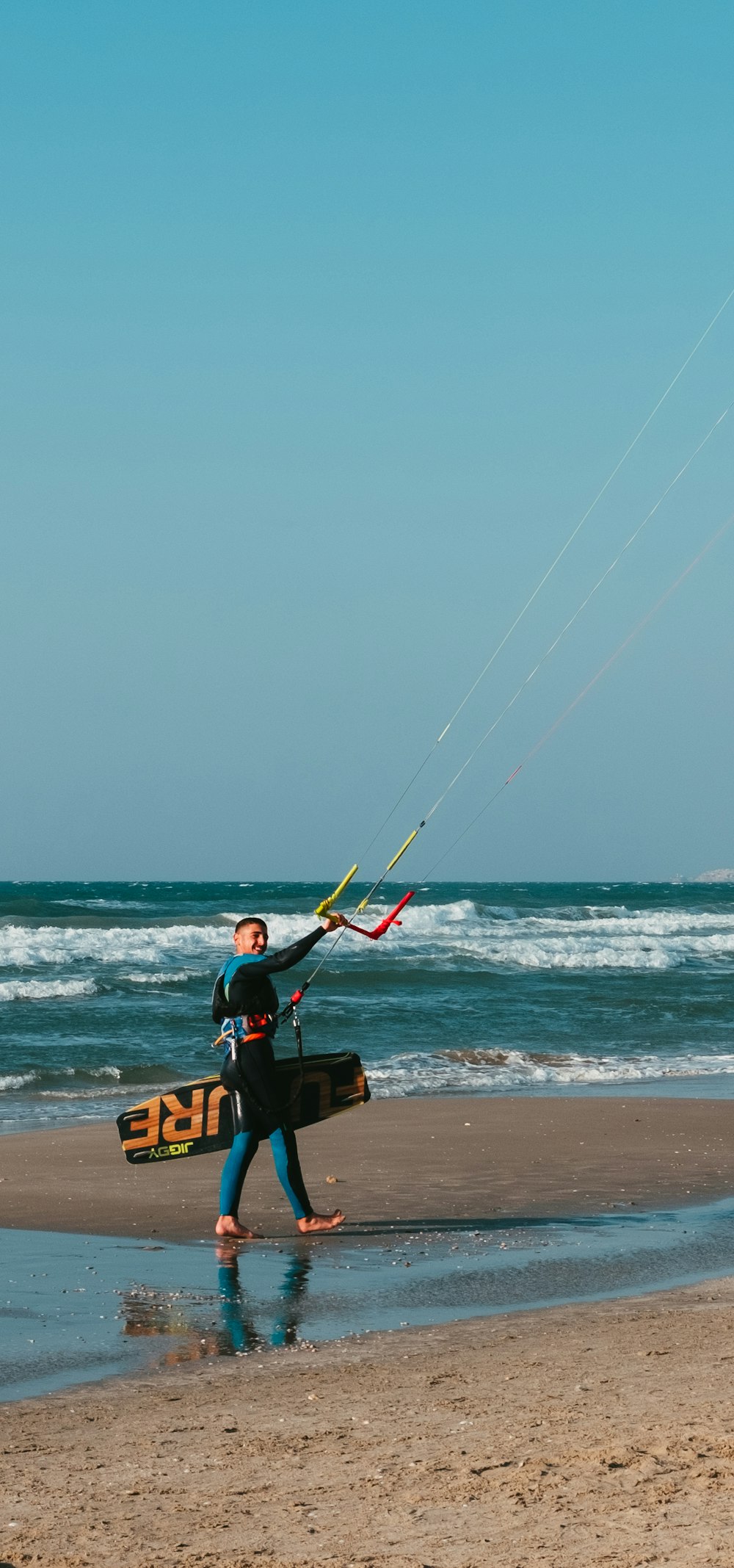 man in yellow shirt and black shorts sitting on brown wooden board on beach during daytime