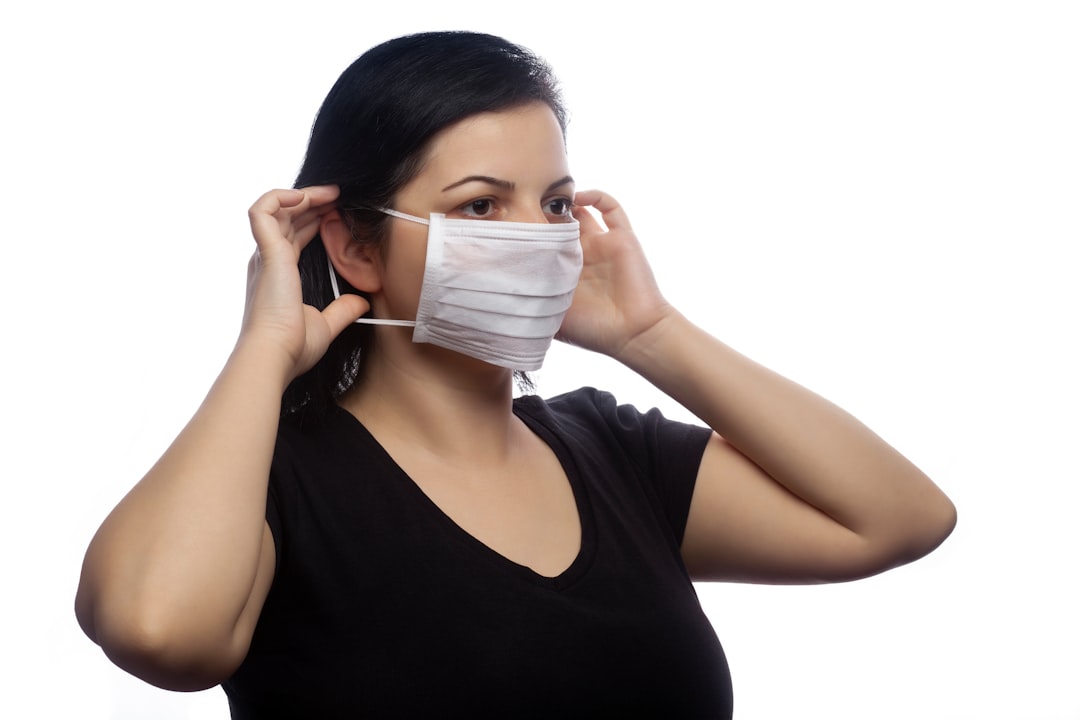 woman in black tank top covering her face with white mask