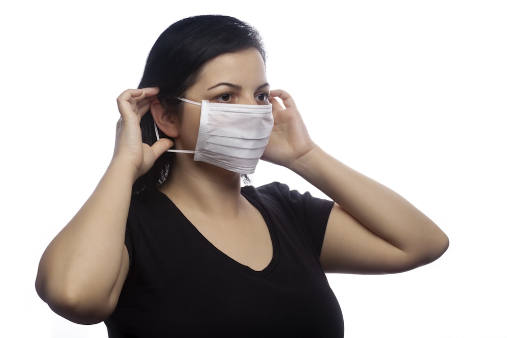 woman in black tank top covering her face with white mask