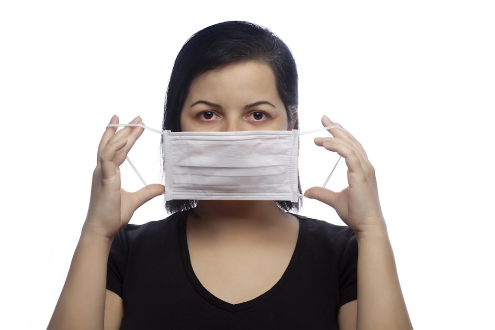 Mujer con camiseta negra sin mangas cubriendo su cara con papel blanco