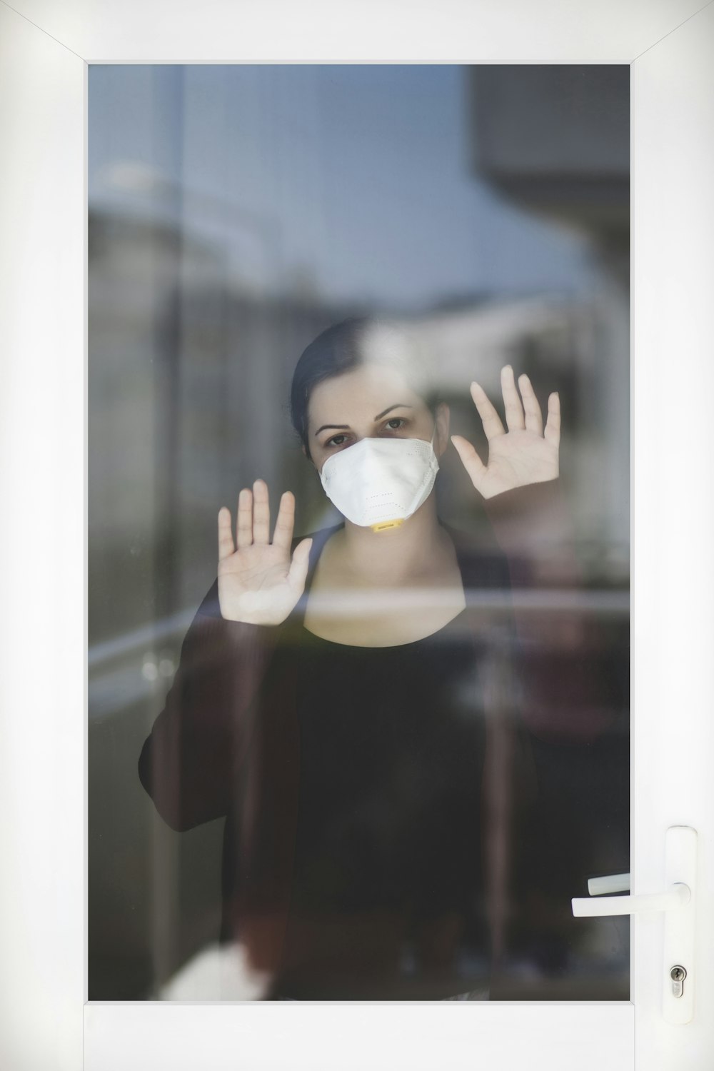 Femme en chemise rouge à manches longues couvrant le visage avec un masque blanc