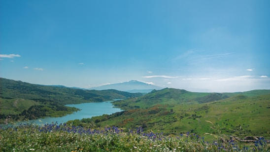 A scenic landscape featuring mountains and a winding river under a clear blue sky.