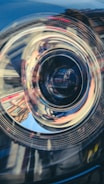 Close-up of a high-end car's headlight with reflections of the surrounding environment.