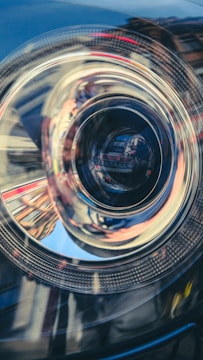 Close-up of a high-end car's headlight with reflections of the surrounding environment.