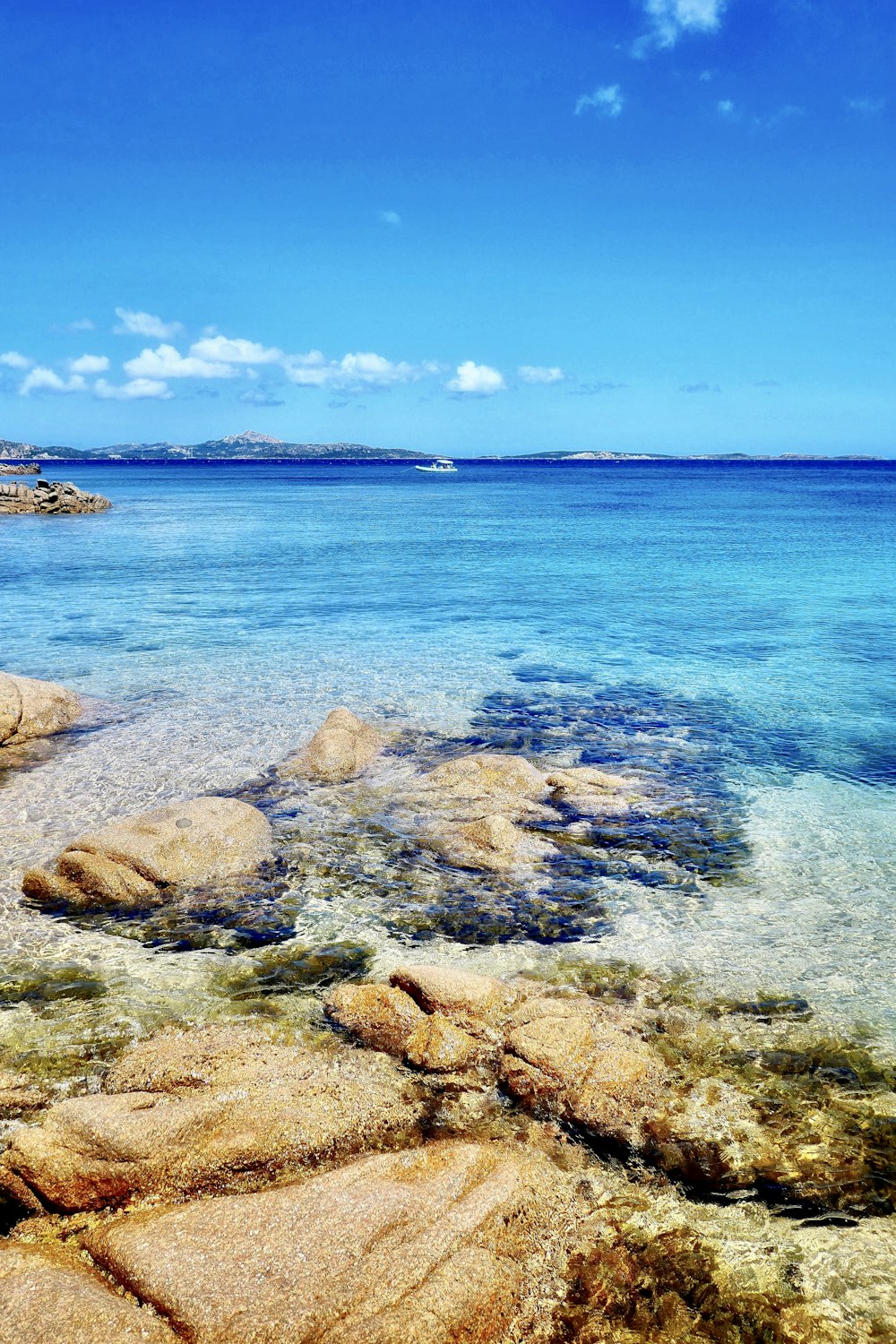 roches brunes sur la mer bleue sous le ciel bleu pendant la journée