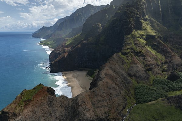 Green and brown mountain beside body of water during daytime — Kauaʻi, United States