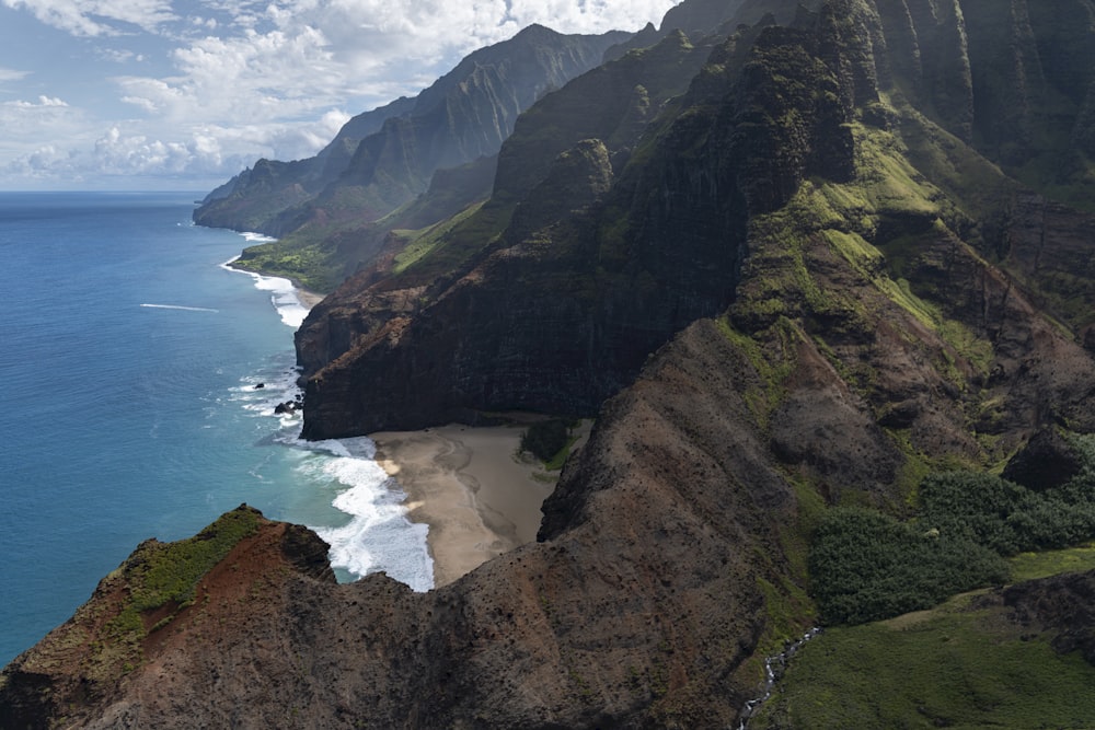 green and brown mountain beside body of water during daytime