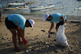 woman in blue t-shirt and white helmet holding white plastic bag on beach during daytime