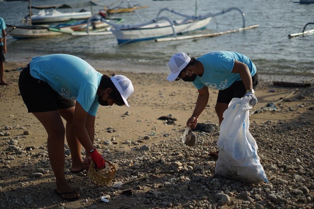 woman in blue t-shirt and white helmet holding white plastic bag on beach during daytime