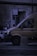 A delivery van is parked on the street next to a smaller car. The van has the words 'Service Partner of DHL' on its side. There is a parking meter and a sign labeled 'PARCHIMETRO' with an arrow pointing to 'TICKET'. The scene takes place in a dimly lit urban environment.