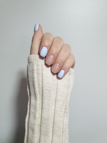 Soft pink nails with minimalist white line art, styled with a cozy sweater background.