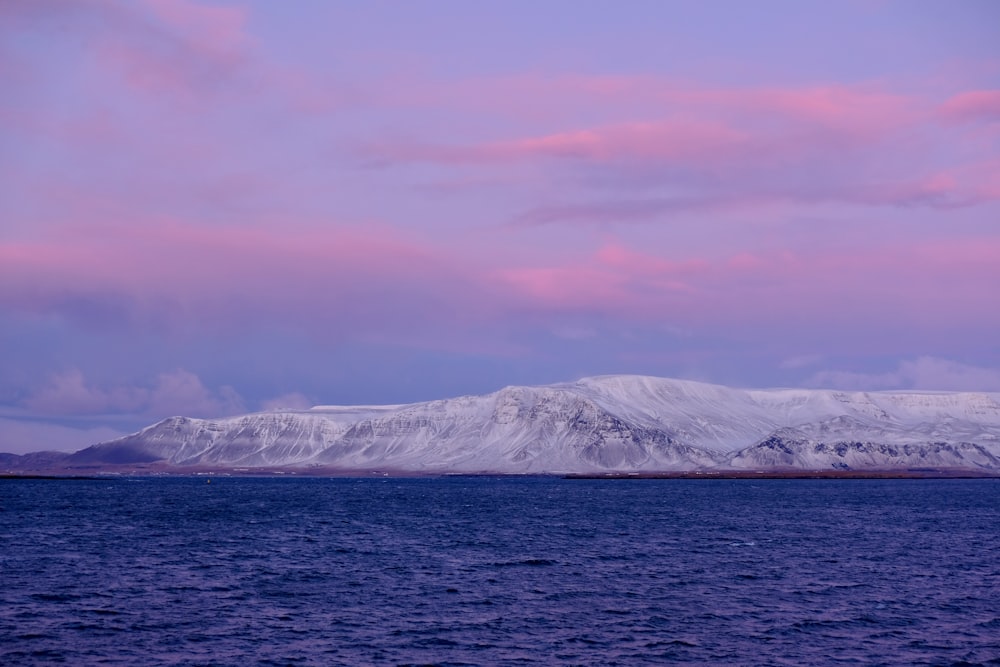 snow covered mountain near body of water during daytime