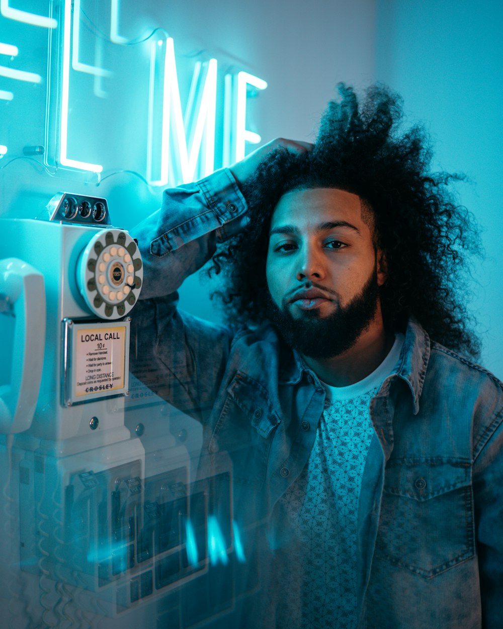 man in blue and white button up shirt holding white rotary phone