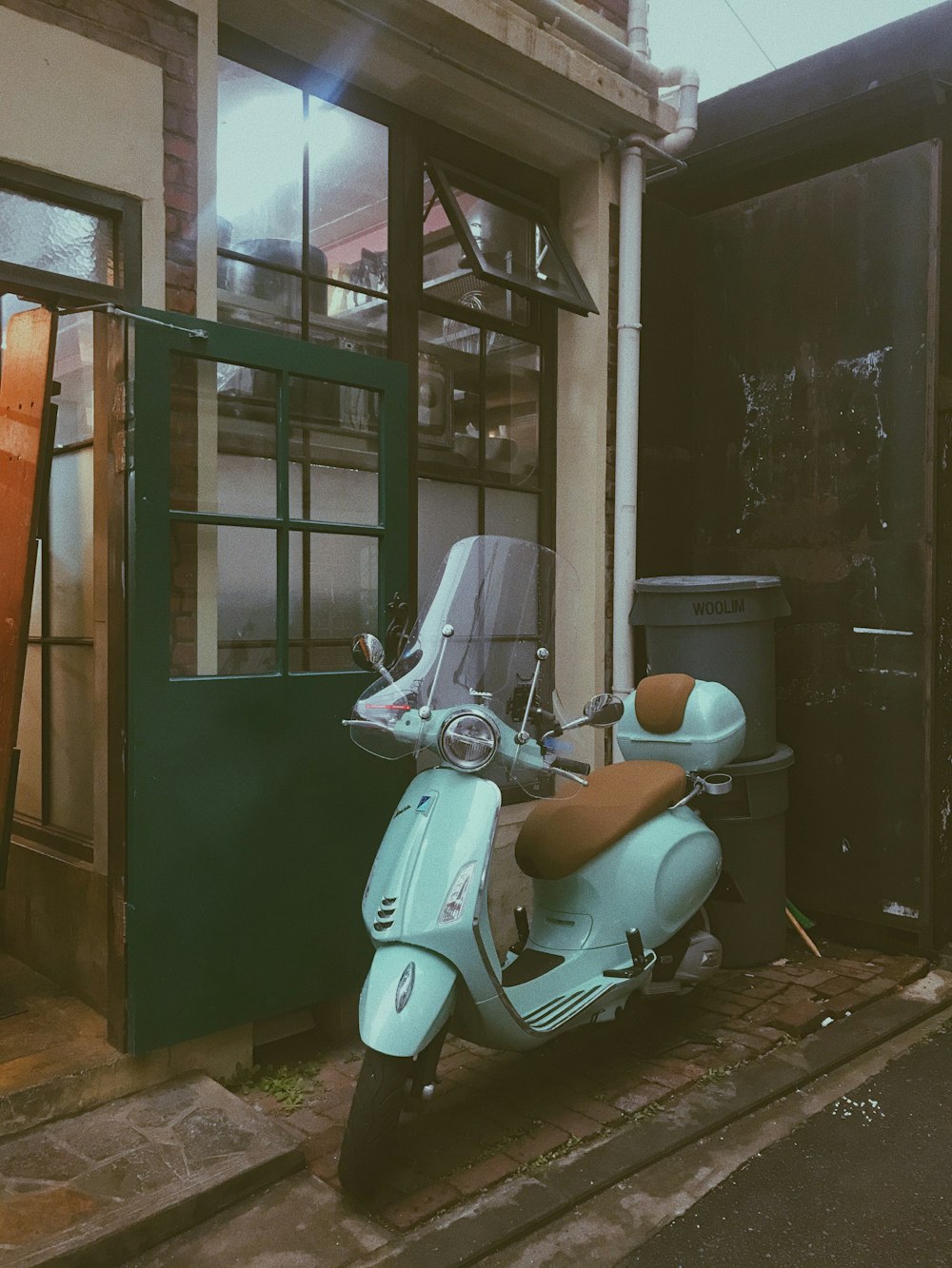 white motor scooter parked beside brown wooden framed glass window