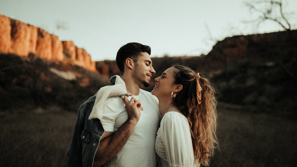 man in black leather jacket kissing woman in white shirt