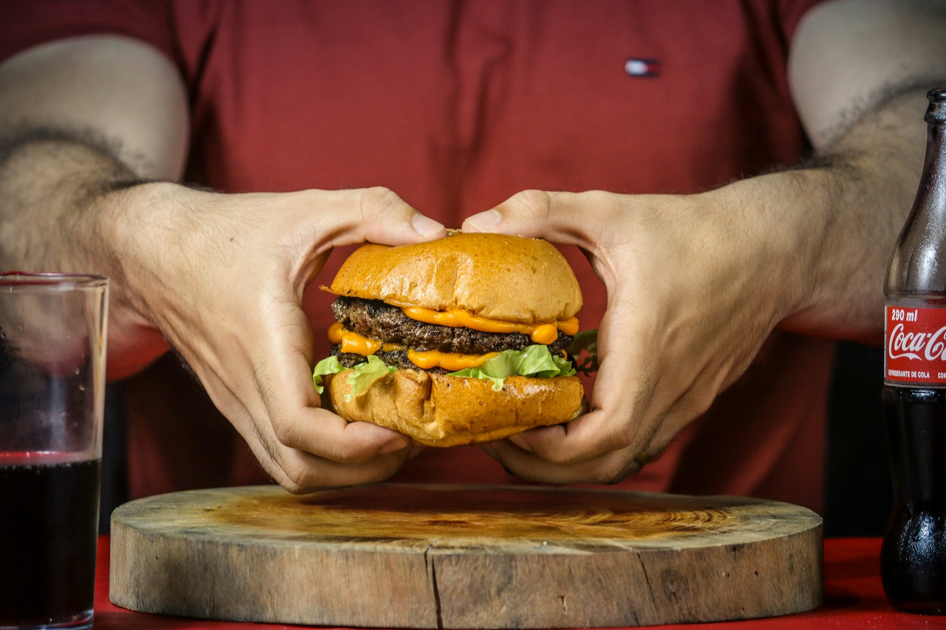 person holding burger with cheese and lettuce