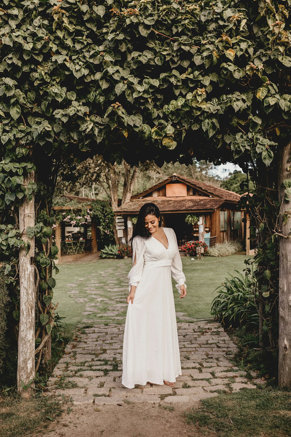 woman in white long sleeve dress standing under green tree during daytime