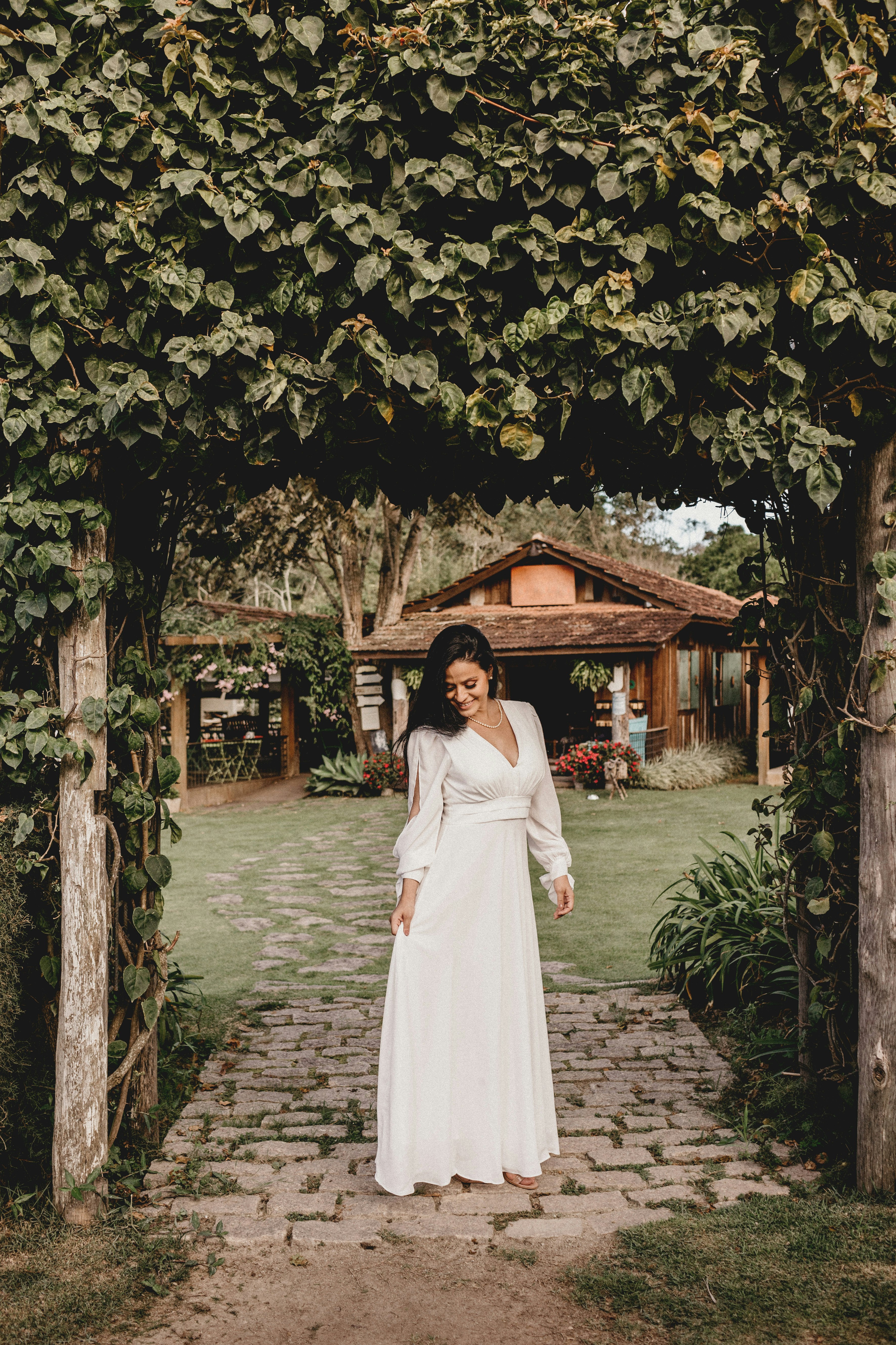 woman in white long sleeve dress standing under green tree during daytime
