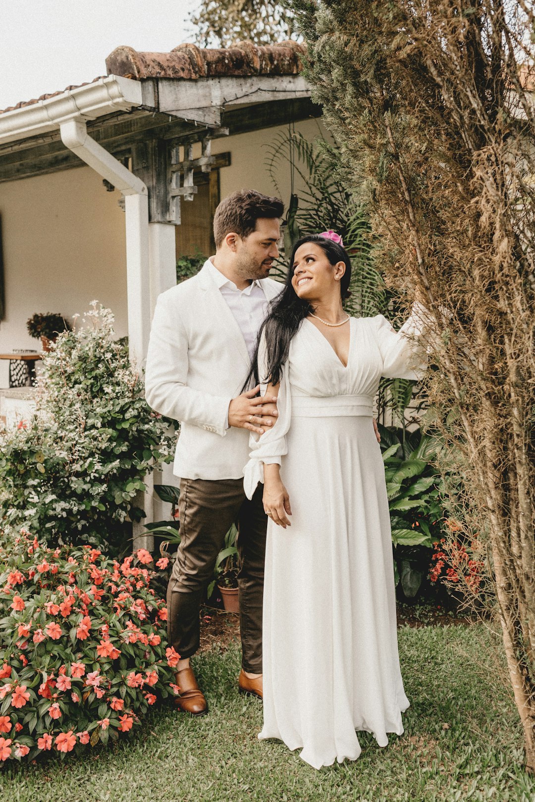 man and woman standing near red flowers