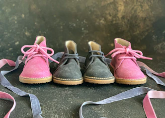 Artistic shot of women's shoes with flowing purple ribbons caught mid-air over a soft dark surface