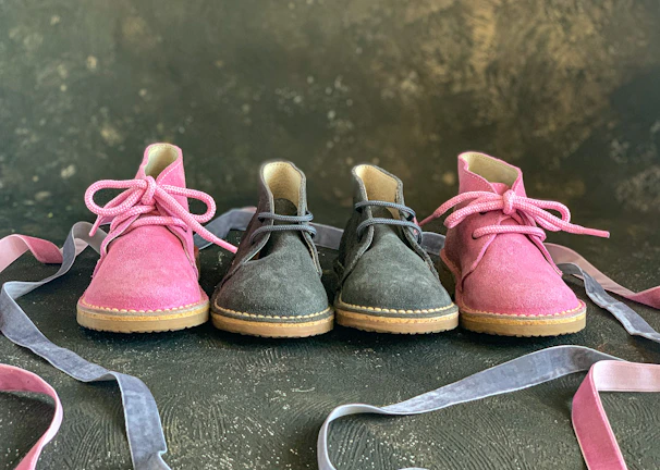 Artistic shot of women's shoes with flowing purple ribbons caught mid-air over a soft dark surface