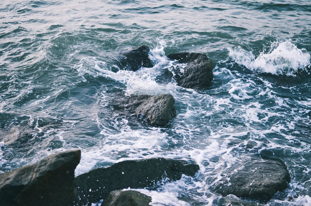 black rock formation beside body of water during daytime