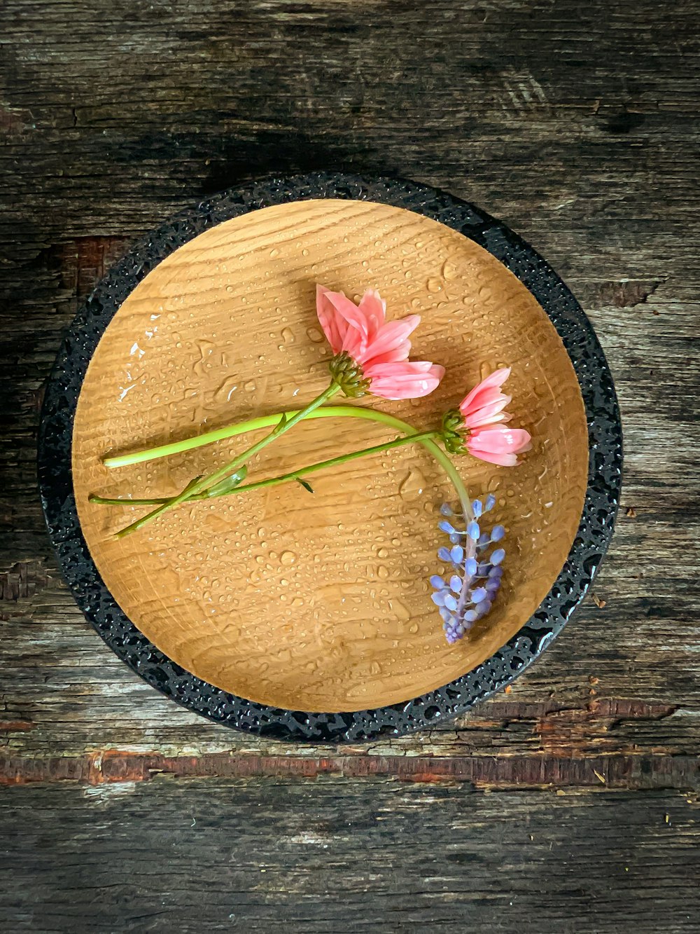 flor rosa y verde en plato redondo de madera marrón