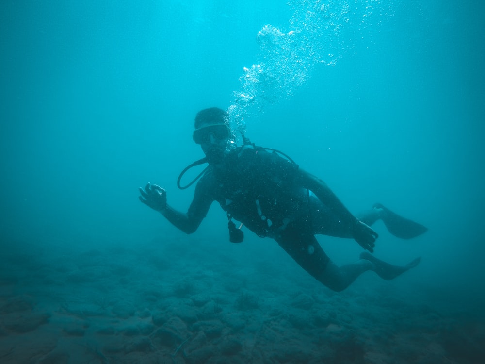 homem em wetsuit preto sob a água