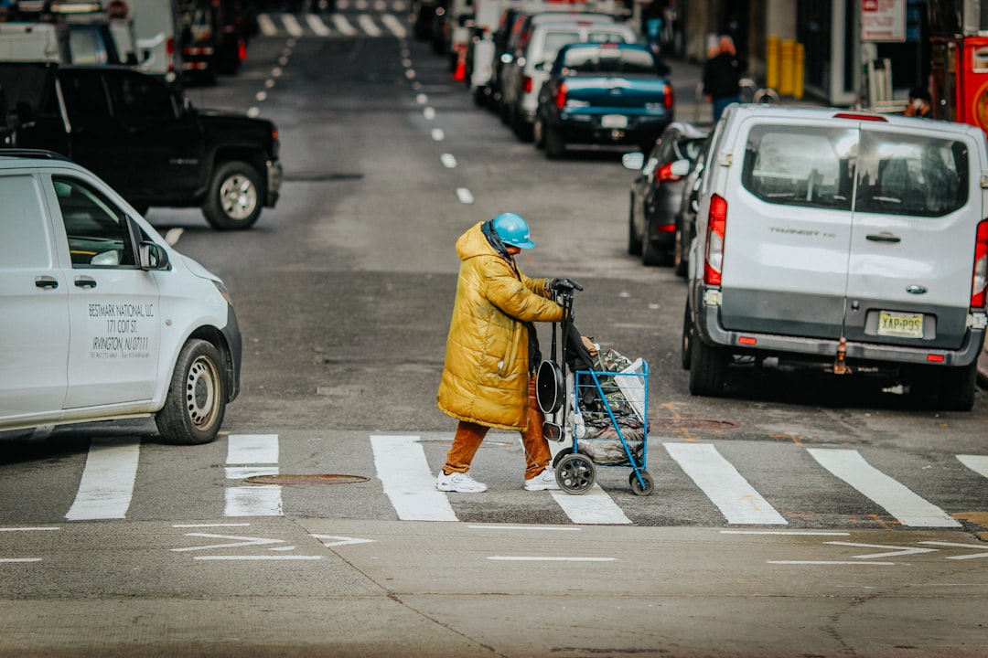 man in yellow jacket and black pants walking on pedestrian lane during daytime