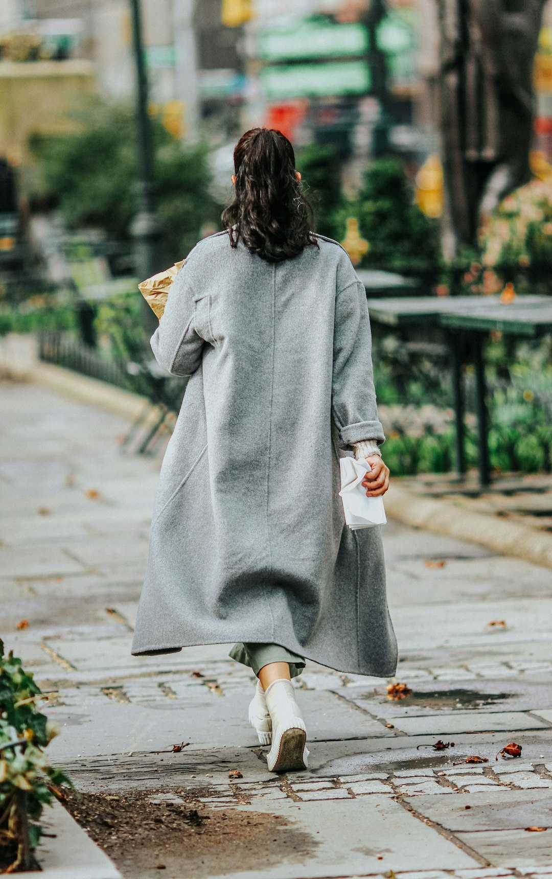 woman in gray robe walking on sidewalk during daytime