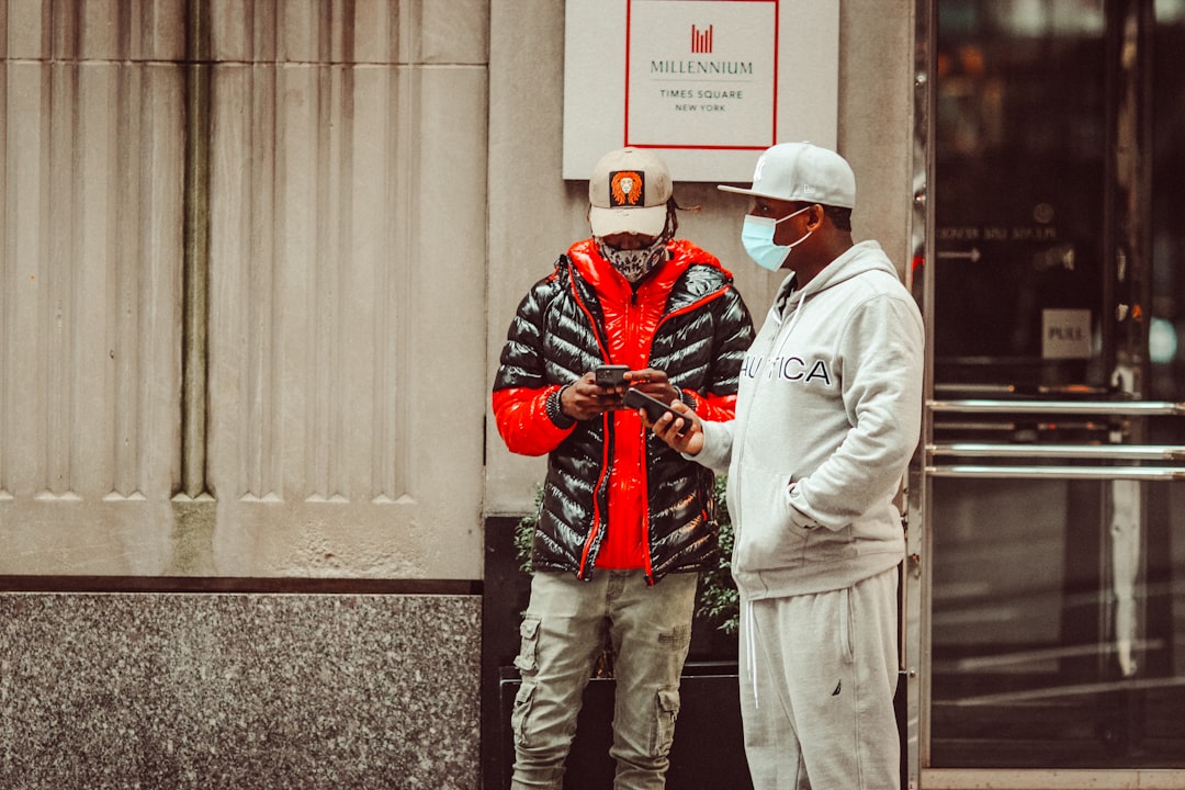 man in red and black jacket standing beside man in white jacket