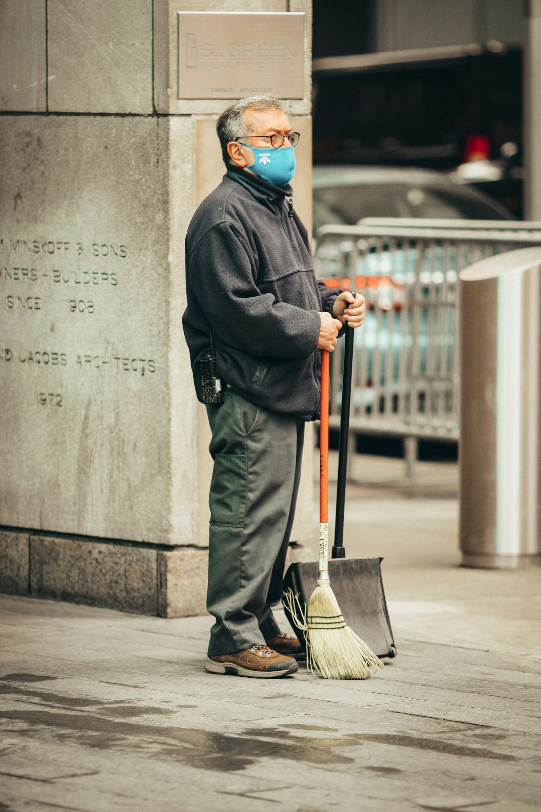 man in black coat and blue hijab standing beside gray concrete wall during daytime