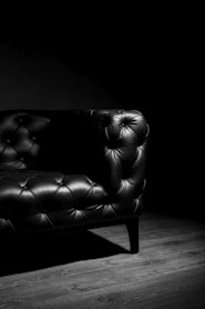 black leather loveseat on brown wooden floor