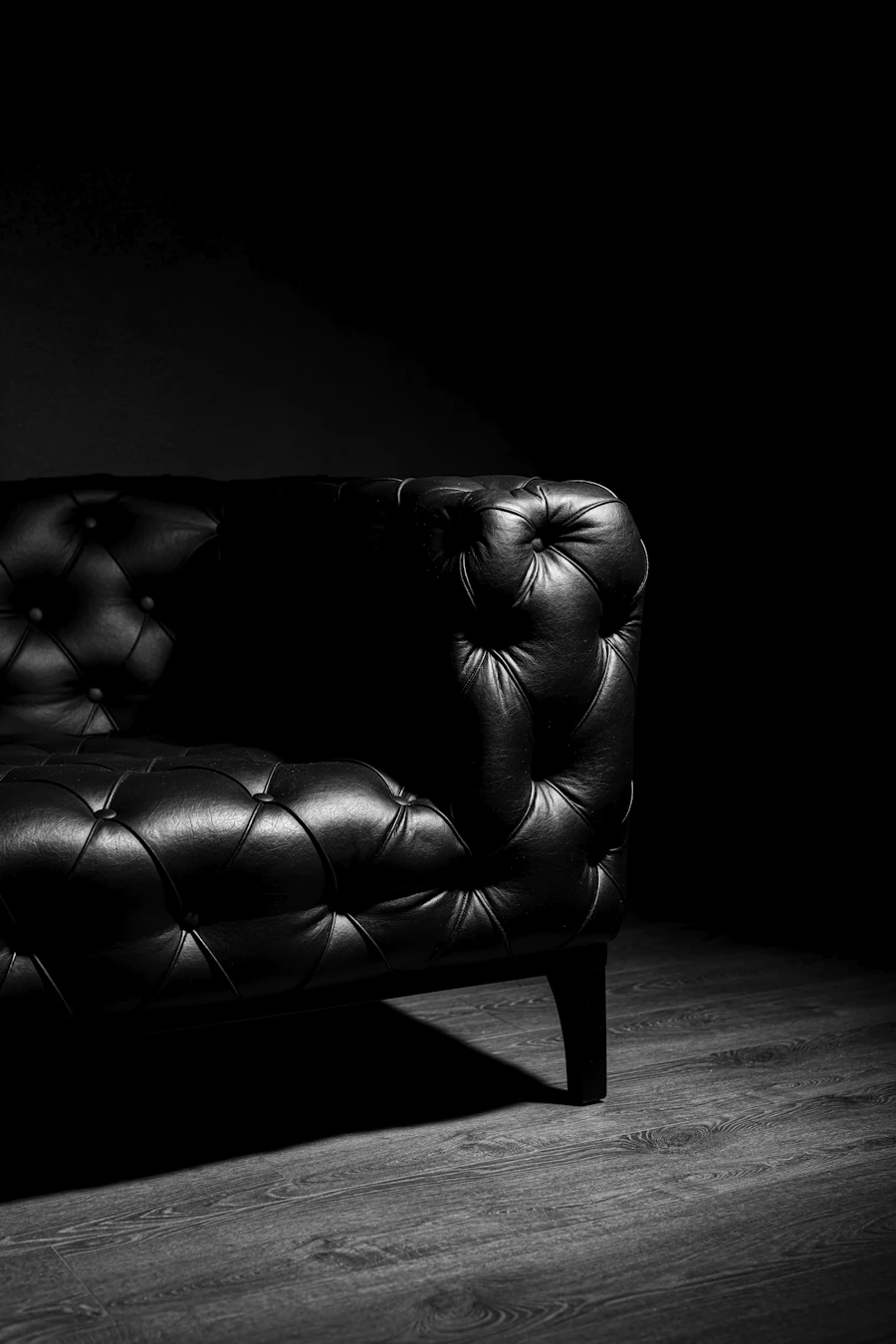 A dark leather sofa on a timber floor in a low-lit room